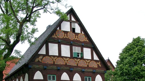 A traditional half-timbered house with a stone base and a steeply pitched roof.