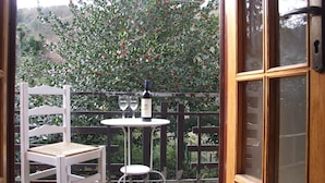 A patio area with a white chair, a small table, and a bottle of wine. - Apartment- Rosa 4+2 - Two Bedroom Apartment, Sleeps 6 (Val Canina)