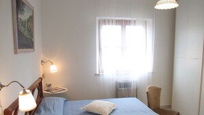 A bedroom with a bed, a chair, a lamp, a window with curtains, and a painting on the wall. - Apartment- Rosa 4+2 - Two Bedroom Apartment, Sleeps 6 (Val Canina)