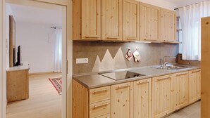 A modern kitchen with wooden cabinets, a stainless steel sink, and a built-in oven. - Borésc with private bio sauna (Livinallongo del col di lana)
