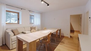 A modern, well-lit room with a wooden dining table, chairs, and a sofa. - Borésc with private bio sauna (Livinallongo del col di lana)