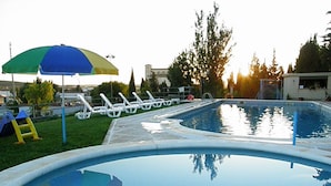Una piscina con sillas de descanso y un paraguas colorido.