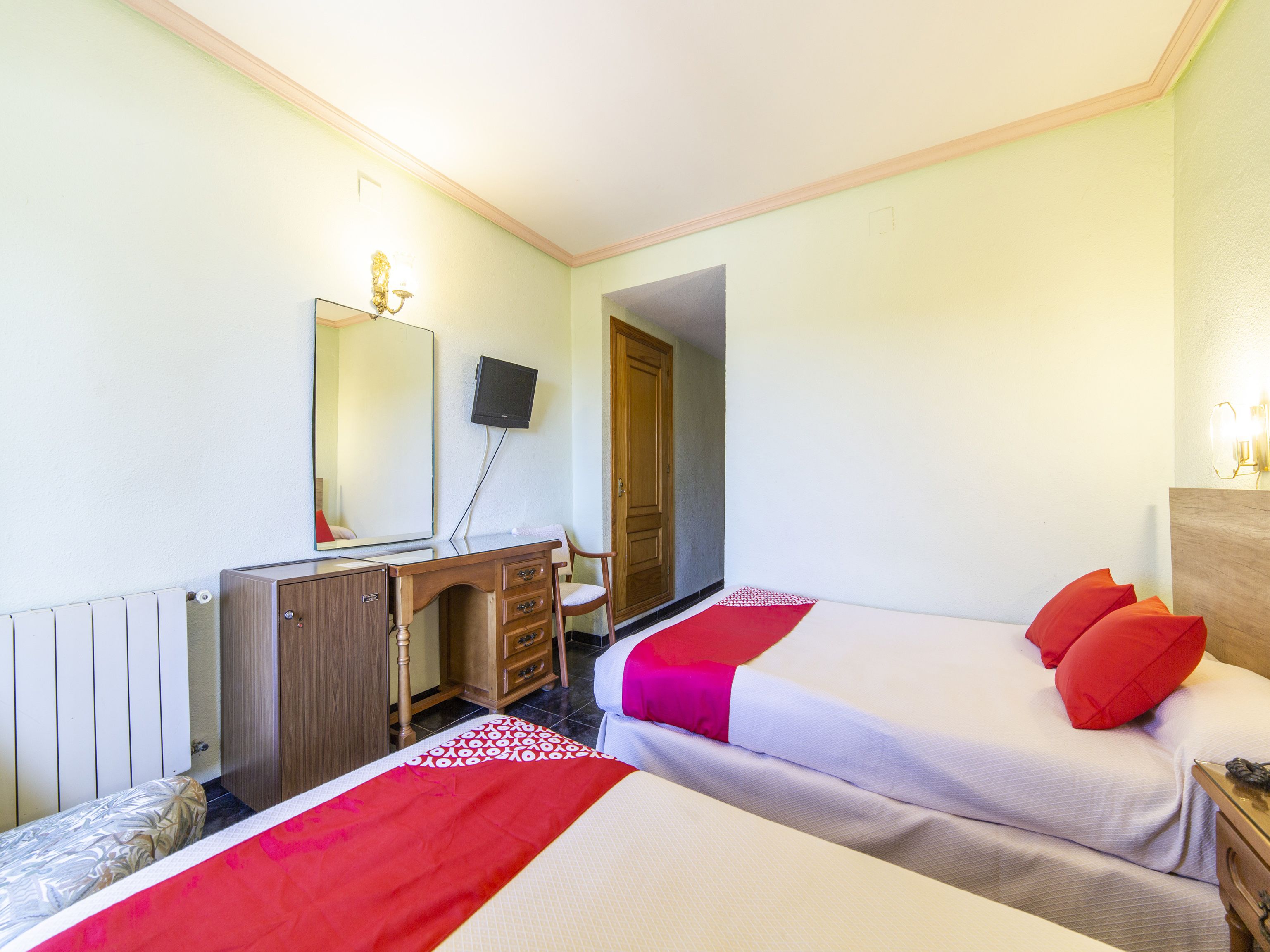 A hotel room with two beds, a desk, a chair, a television, and a wardrobe.
