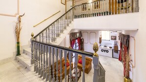 Una imponente escalera con candelabro, una recepción y un sofá de cuero.