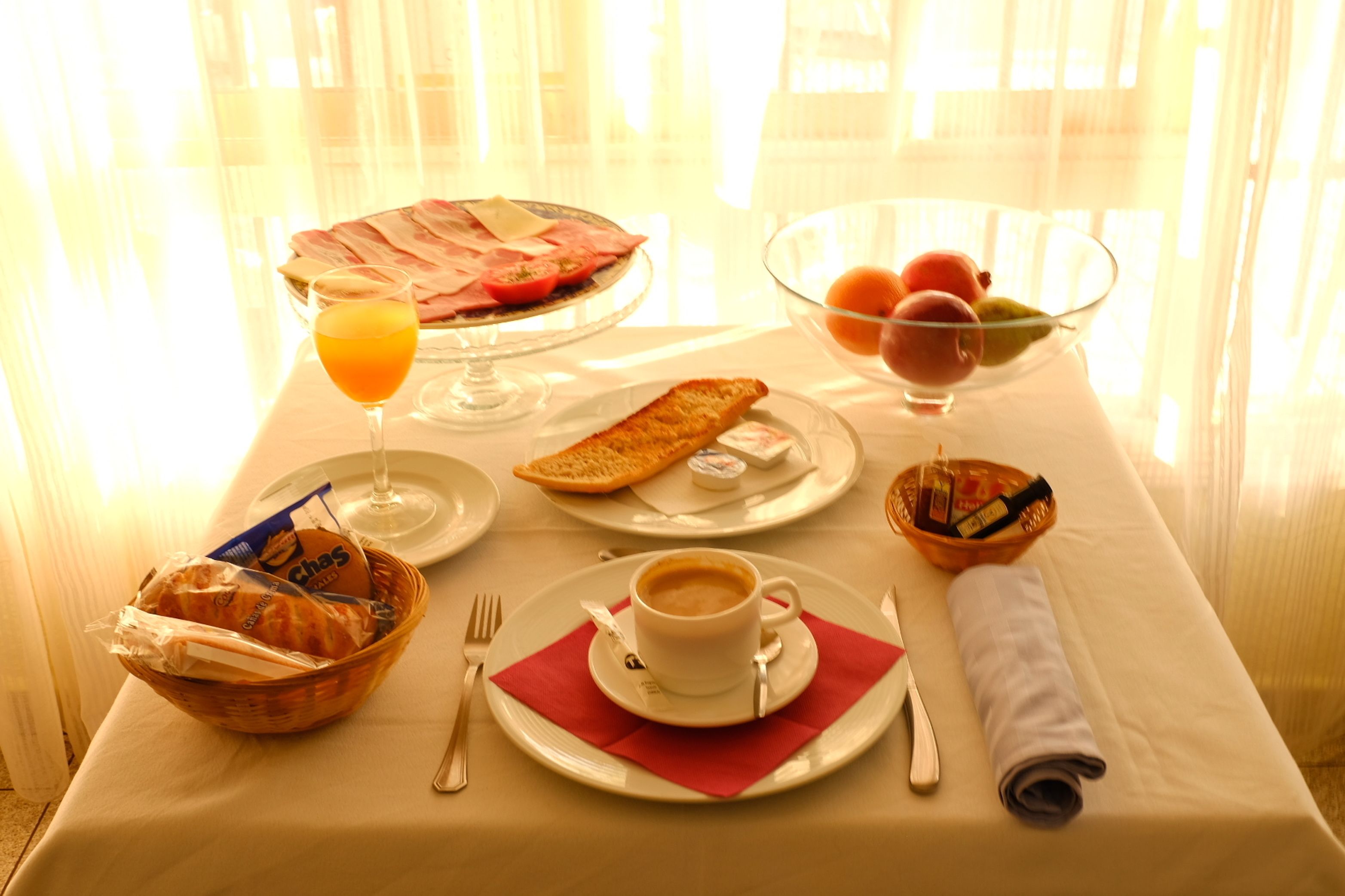 A breakfast setting with a plate of eggs, toast, and fruit, a glass of orange juice, and a cup of coffee on a table.