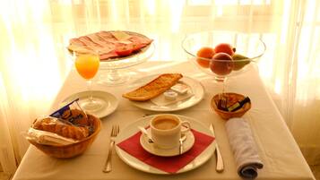 A breakfast setting with a plate of eggs, toast, and fruit, a glass of orange juice, and a cup of coffee on a table.