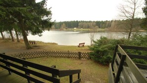 A lakeside park with wooden benches and a wooden deck overlooking the water. - Holiday park- Nurdach (Clausthal)