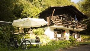 A rustic wooden cabin with a balcony, a bicycle, and a bench. - Haus 1  - Typ C (kombiniert) (Schönecken)