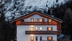 A two-story chalet with a balcony, surrounded by snow-covered mountains. - Sas Ciapel with private bio sauna (Livinallongo del col di lana)