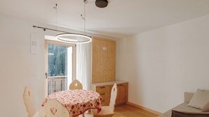 A room with a dining table, chairs, a sofa, a wooden cabinet, and a window with curtains. - Aurone with private bio sauna (Livinallongo del col di lana)