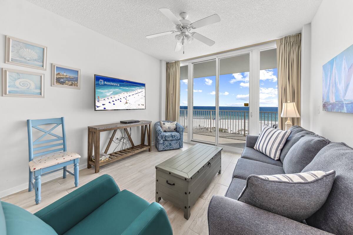 A living room with a sofa, armchairs, a coffee table, a TV, and a ceiling fan.