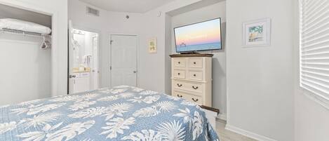 A bedroom with a bed, a television, a dresser, and a closet.