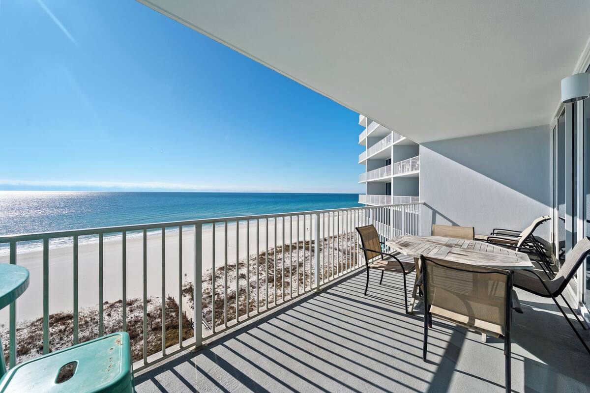 A balcony with a view of the beach and ocean.