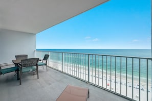 En balkon med fletmøbler med udsigt over stranden.