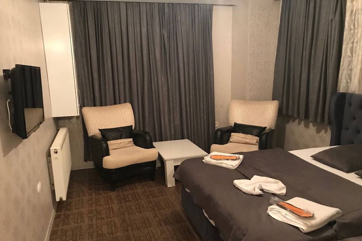 Une chambre d’hôtel avec un lit, deux fauteuils, une petite table et un téléviseur.
