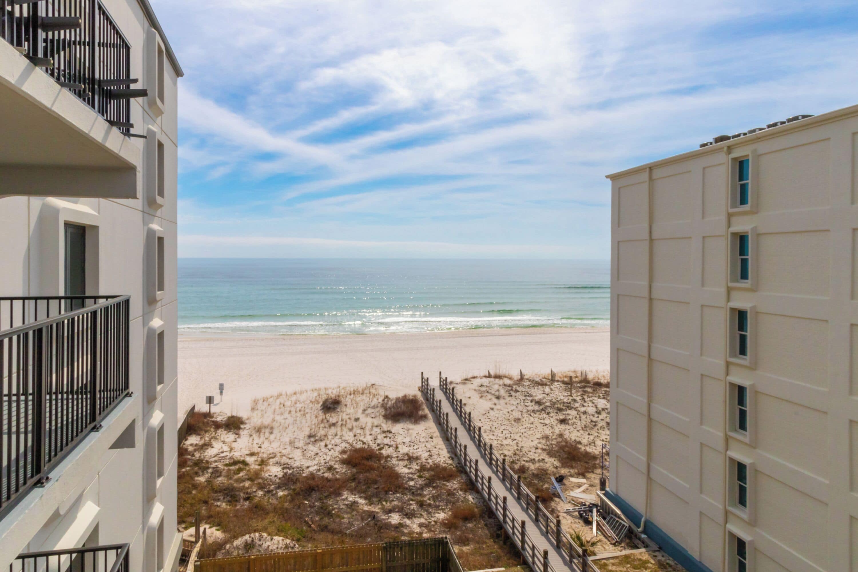 A beachfront view from a balcony overlooking a sandy beach and ocean.