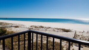 A beach view from a balcony with a railing, sandy beach, and ocean. - Island Sunrise Condos by Hosteeva (Gulf Shores)