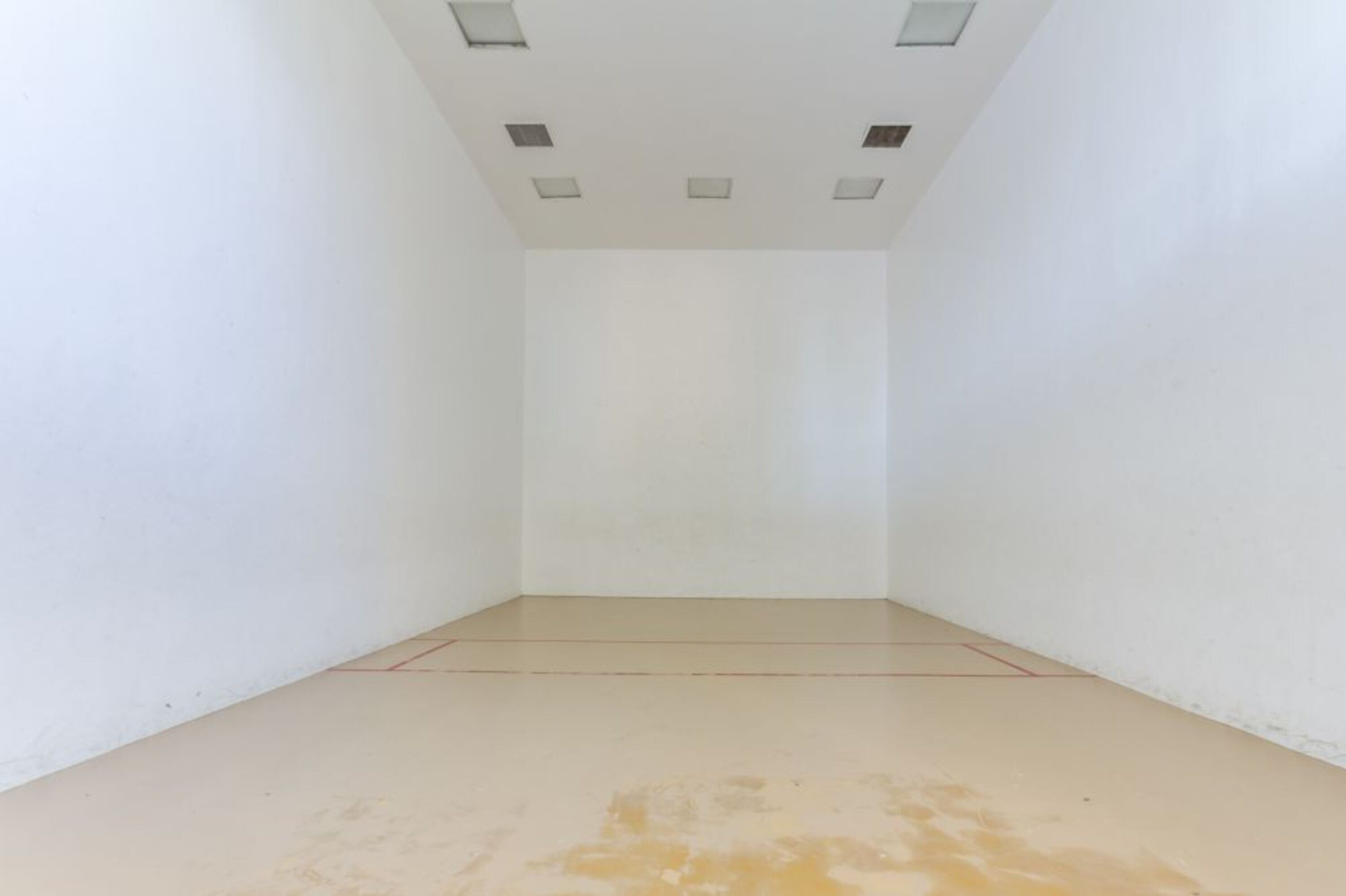 A room with white walls and a light-colored floor, featuring a ceiling with recessed lighting.