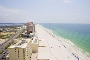 A beachfront hotel with multiple buildings, a sandy beach, and a clear view of the ocean.