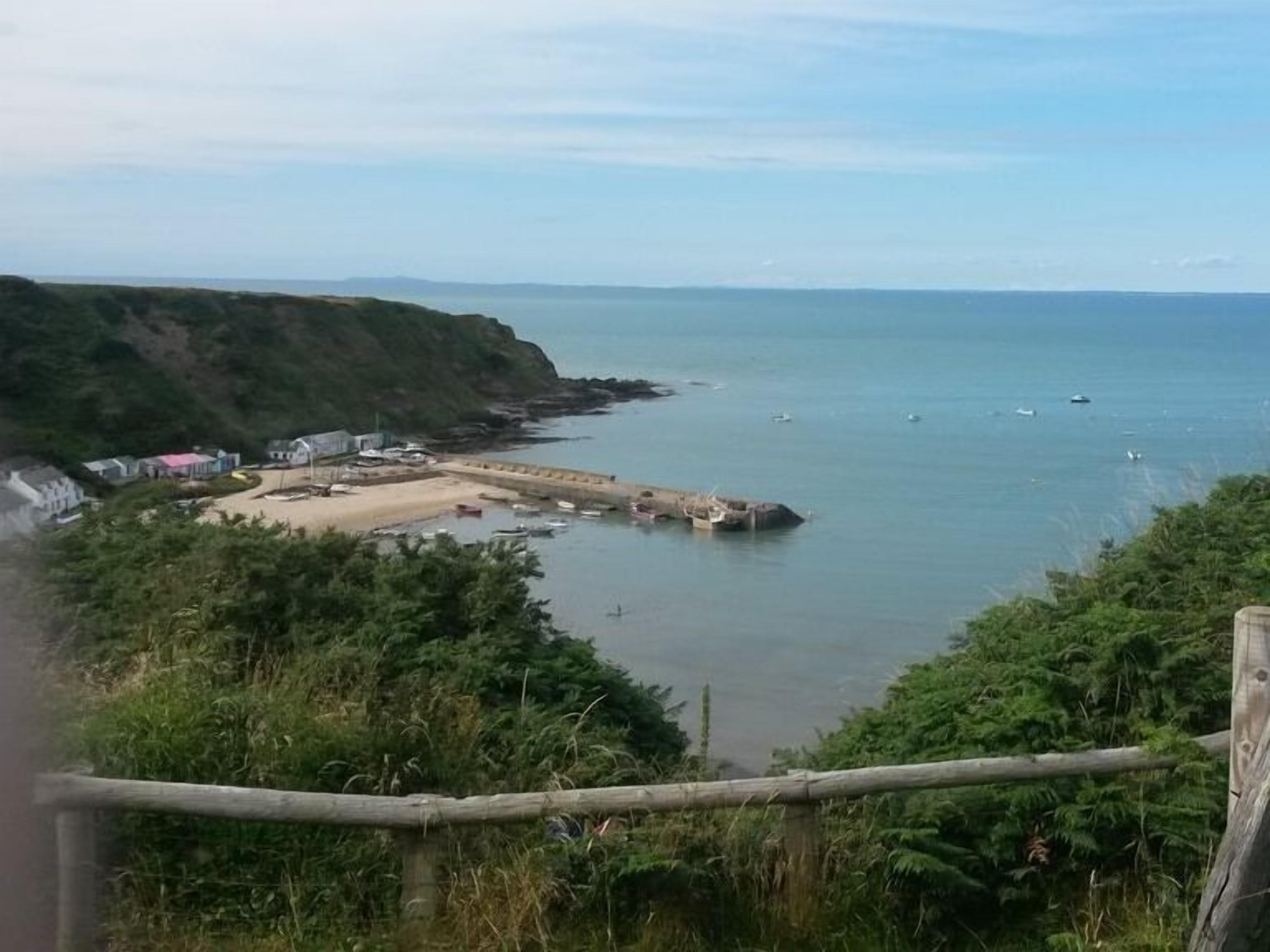 A coastal view with a sandy beach, a pier, and boats.