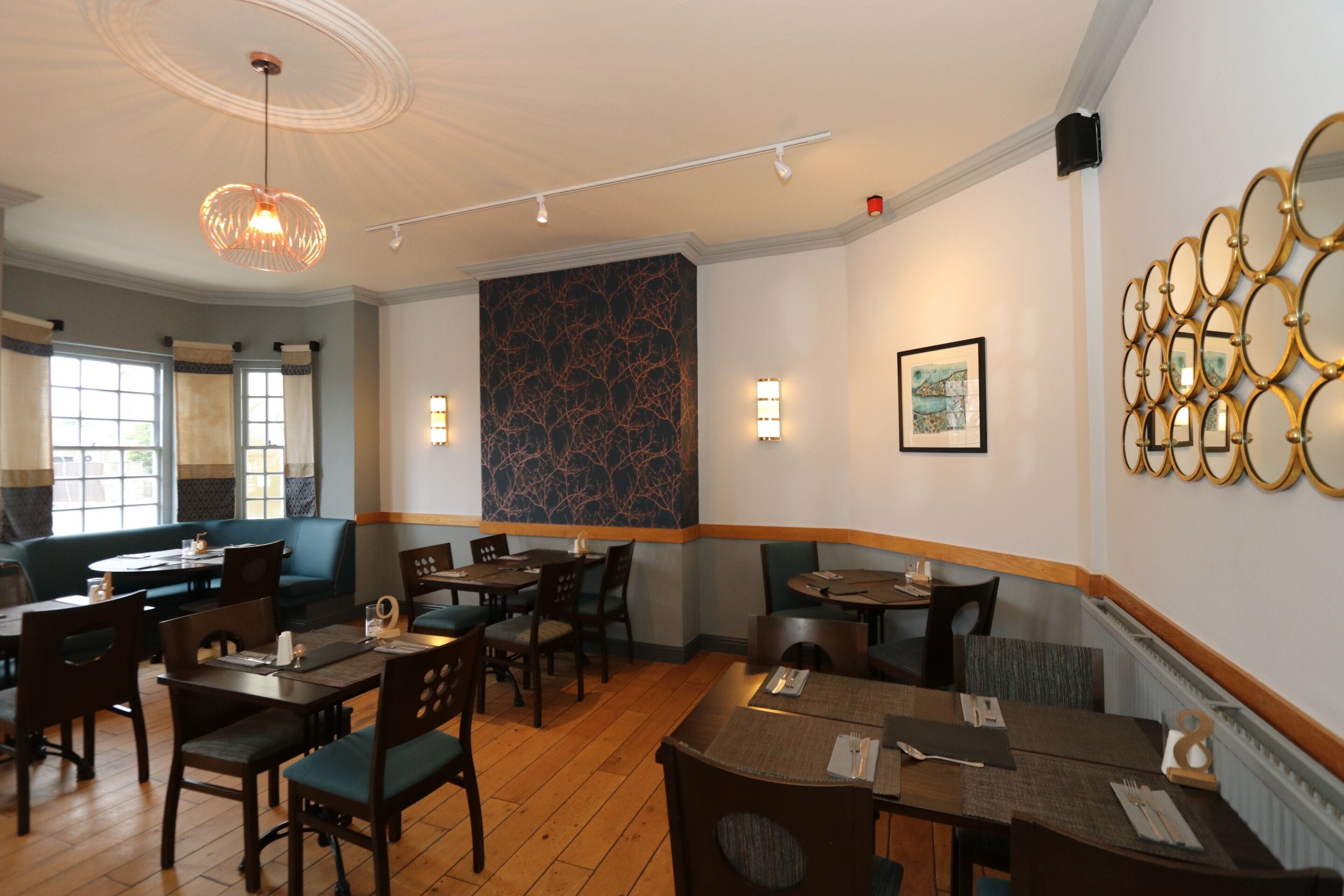 A restaurant with wooden tables and chairs, a patterned wall, and a ceiling light fixture.