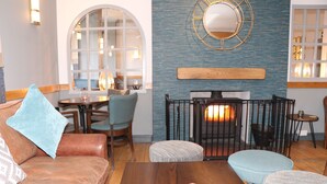 Un salon chaleureux avec une cheminée, un canapé en cuir et une table basse en bois.