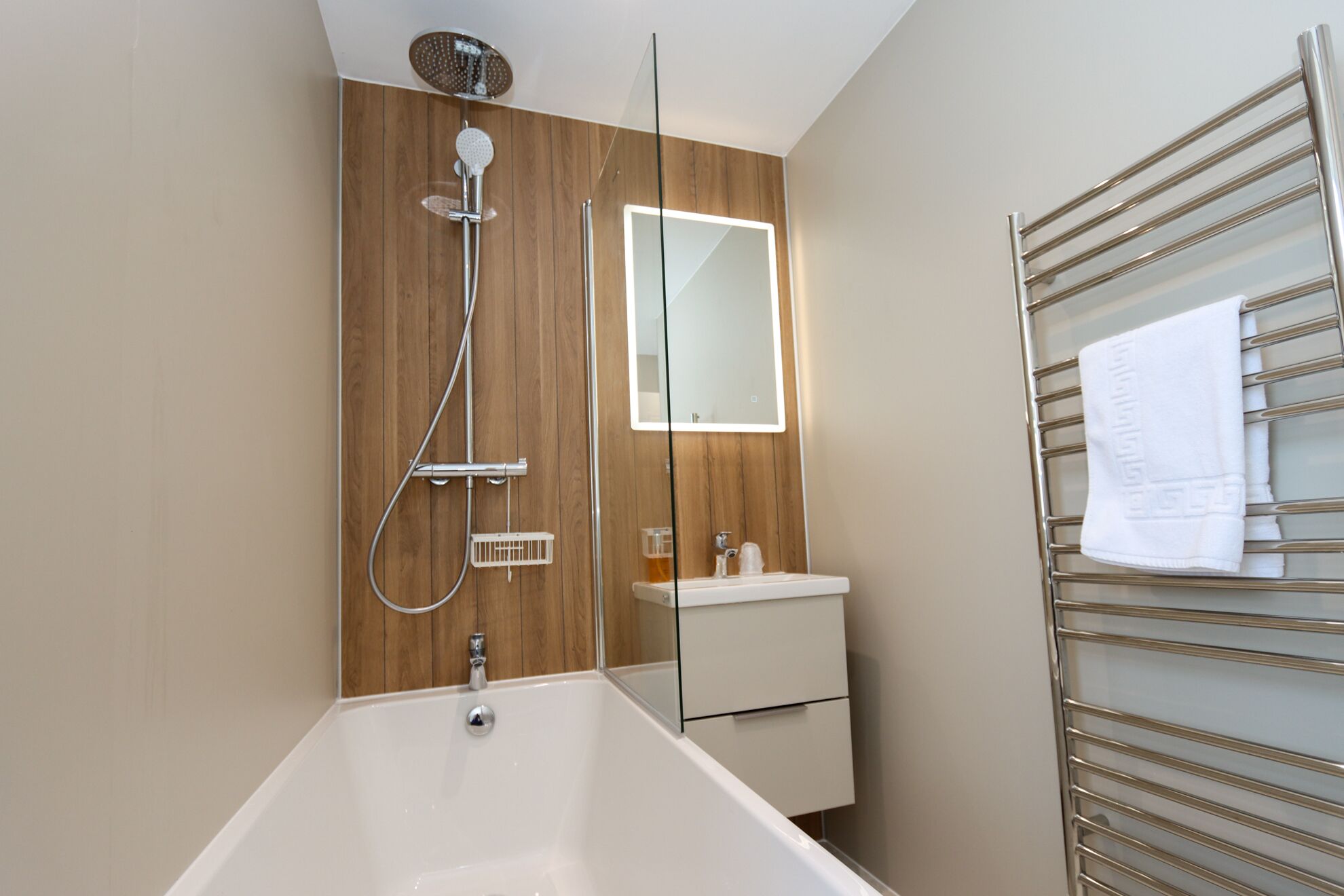 A modern bathroom with a bathtub, a shower, a sink, and a towel rack.