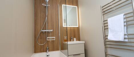 A modern bathroom with a bathtub, a shower, a sink, and a towel rack.