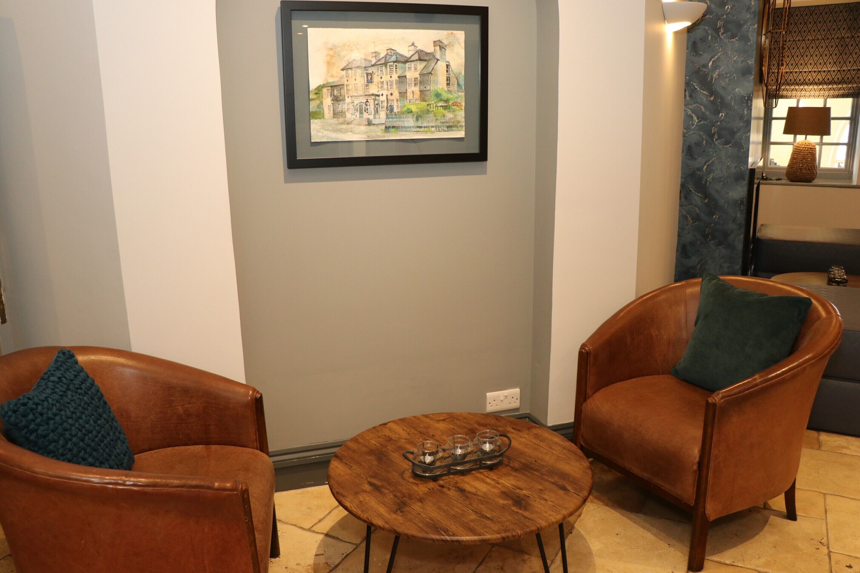 Una habitación con dos sillones de cuero, una mesa de centro de madera y un cuadro enmarcado en la pared.