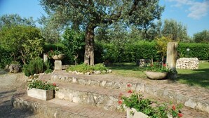 A garden with stone steps leading to a seating area, surrounded by various plants and trees. - Dante/Pino - Two Bedroom Apartment, Sleeps 6 (Tocco da Casauria)