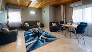 A living room with a sofa, a coffee table, and a dining area with chairs and a table. - Pine Wood Apartment 7 (Zalakaros)