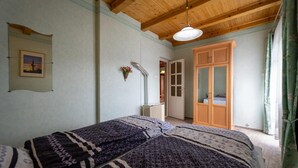 A bedroom with two beds, a wooden ceiling, a door leading to another room, and a hanging light fixture. - Pine Wood Apartment 7 (Zalakaros)