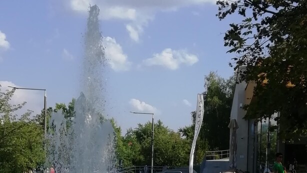 A public fountain with water jets, surrounded by a metal railing and a paved walkway. - Pine Wood Apartment 7 (Zalakaros)
