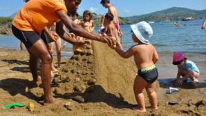 A beach scene with people playing and building sand structures. - Trilocale classic - Two Bedroom Apartment, Sleeps 5 (Porto Azzurro)