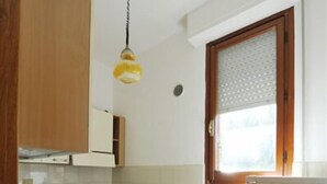 A kitchen with wooden cabinets, a stainless steel sink, a stove, and a refrigerator.