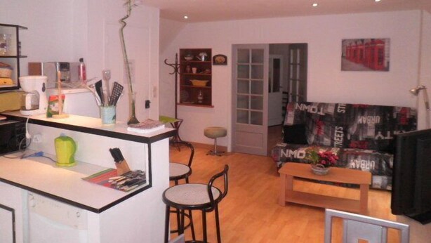 Een ruimtelijk ingerichte leefruimte met kitchenette, eethoek en een zithoek.