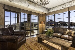 A spacious room with leather sofas, a wooden coffee table, and large windows offering views of the outside. - Bass Pro Shops Angler's Lodge (Springfield)