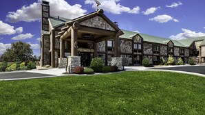 A large, multi-story building with a stone facade, a prominent entrance with a covered porch, and a green roof. - Bass Pro Shops Angler's Lodge (Springfield)