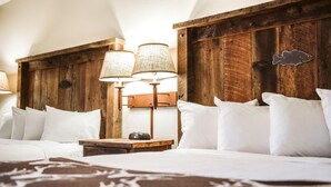 A neatly made bed with white linens, a wooden headboard, and two wall-mounted lamps.