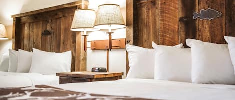A neatly made bed with white linens, a wooden headboard, and two wall-mounted lamps.