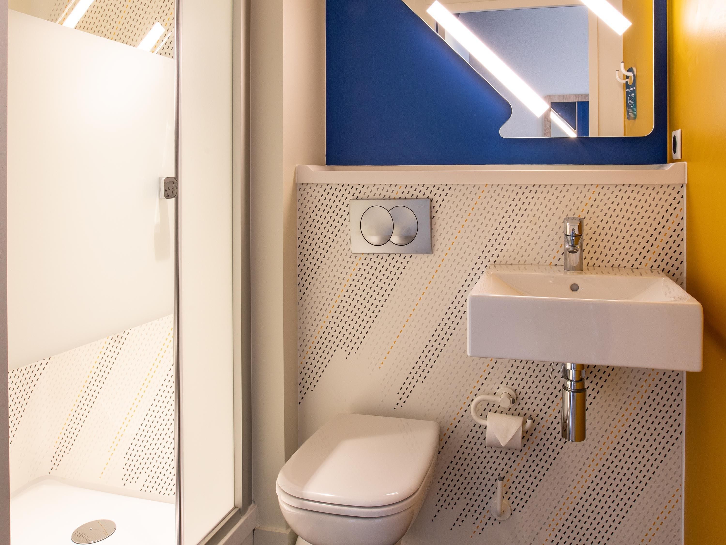 Ein Badezimmer mit einer weißen Toilette, einem Waschbecken mit Spiegel darüber und einer Wand mit Muster.