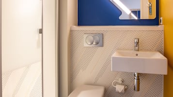 Een badkamer met douche, toilet, wastafel en een blauwe accentmuur.