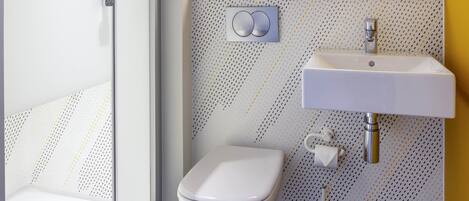 A bathroom with a white toilet, a sink, and a shower area.