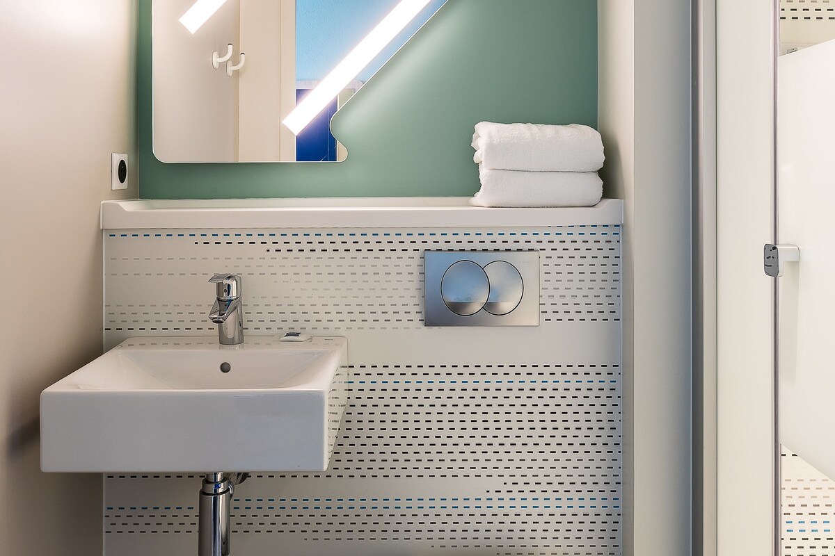 Une salle de bain avec un lavabo blanc, des toilettes et un espace douche.