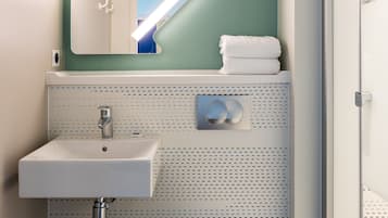A bathroom with a white sink, a toilet, and a shower area.
