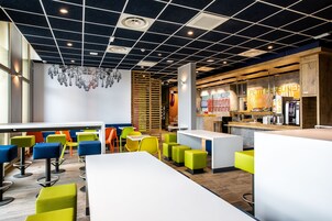 Un café moderno con asientos de colores, una zona de bar y un tablero de menú visible.