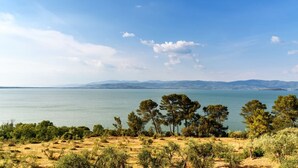 A coastal landscape with a clear view of the sea and distant mountains.