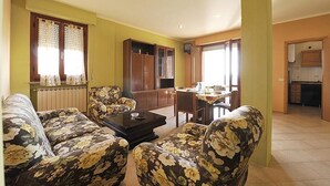 A living room with floral sofas, a coffee table, and a dining area with a table and chairs.