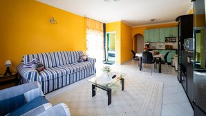 A living room with a striped sofa, a glass coffee table, and a dining area with a table and chairs.