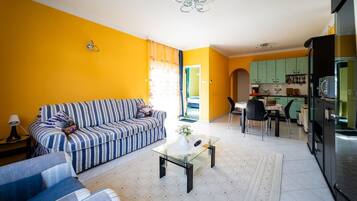 A living room with a striped sofa, a glass coffee table, and a dining area with a table and chairs.
